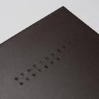 Dark brown notebook with embossed text on a beige background