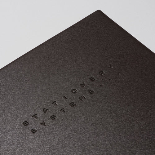 Dark brown notebook with embossed text on a beige background